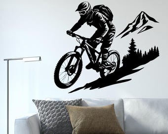May include: Black and white silhouette wall decal of a mountain biker riding downhill with a mountain in the background.