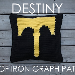May include: A black crochet cushion with a yellow crocheted symbol of a T in the centre. The cushion has the text "DESTINY" above it and "RISE OF IRON GRAPH PATTERN" below it.