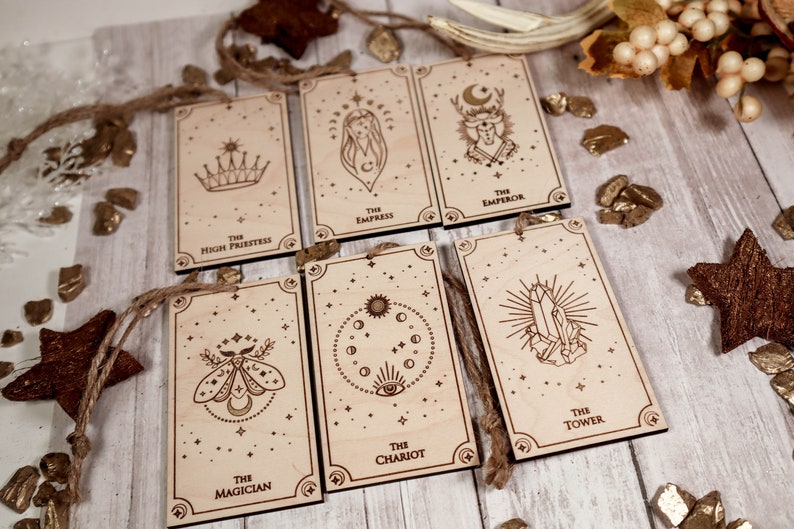 May include: Seven wooden ornaments with a star design and a tarot card image on each. The cards are "The High Priestess", "The Empress", "The Emperor", "The Magician", "The Chariot", "The Tower", and "The Star".