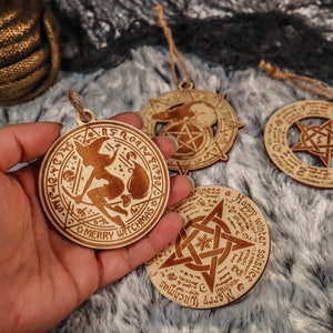May include: Four wooden ornaments with intricate designs, including a witch flying on a broomstick, a pentagram, and a snowflake. The ornaments are all circular and have a rustic, hand-crafted look.