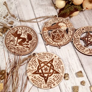 May include: Four wooden Christmas ornaments with a pentagram design and various inscriptions. The ornaments are decorated with a witch, a raven, and the words "Merry Witchmas" and "Happy Winter Solstice".
