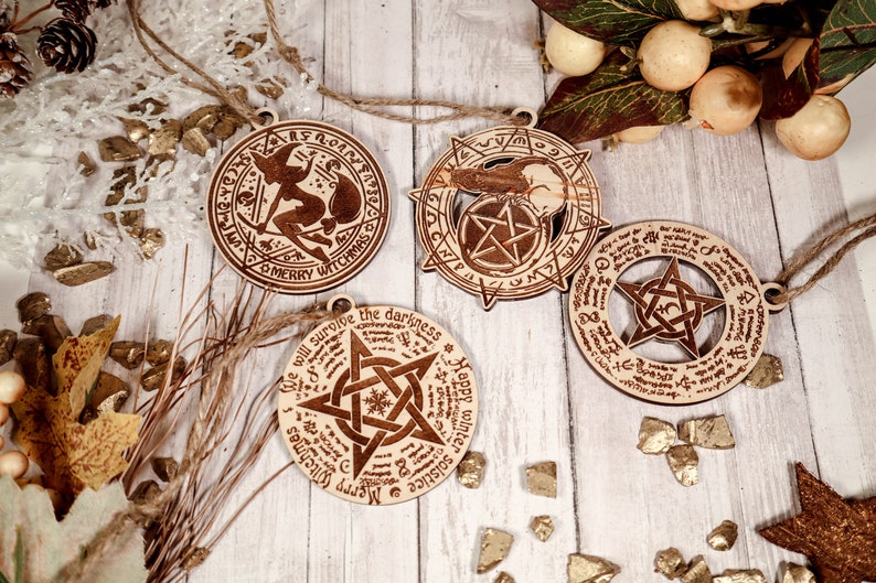 May include: Four wooden ornaments with a witch, a pentagram, and a solstice theme. The ornaments are decorated with intricate designs and text, including "Merry Witchmas" and "We will survive the darkness".
