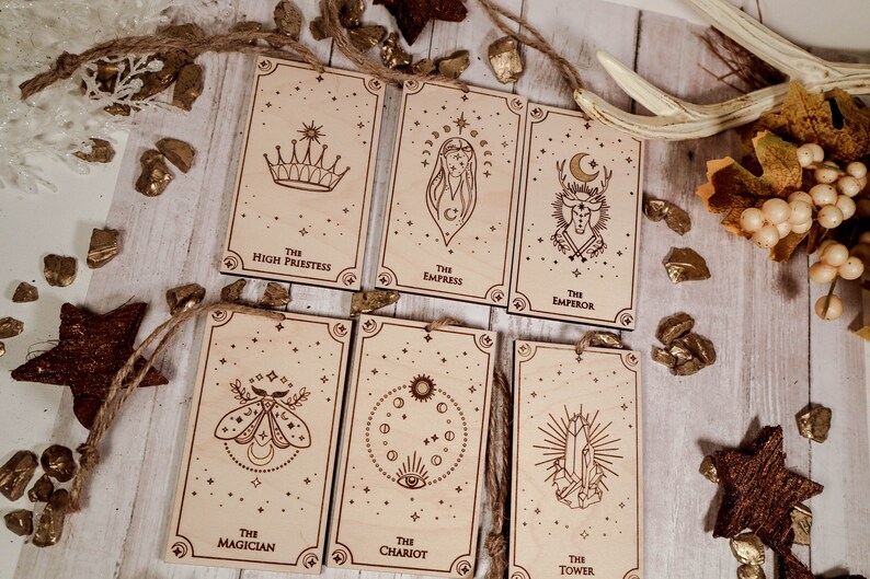 May include: Seven wooden cards with gold foil accents and illustrations of tarot cards. The cards are labeled with the names of the tarot cards: The High Priestess, The Empress, The Emperor, The Magician, The Chariot, The Tower.