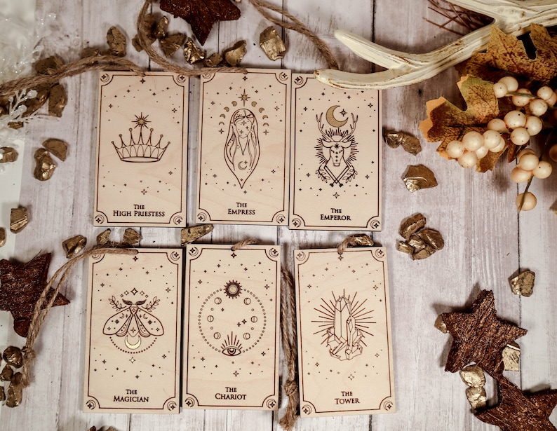 May include: Six wooden tarot cards with gold accents and a star-filled background. The cards feature the following titles: The High Priestess, The Empress, The Emperor, The Magician, The Chariot, and The Tower.