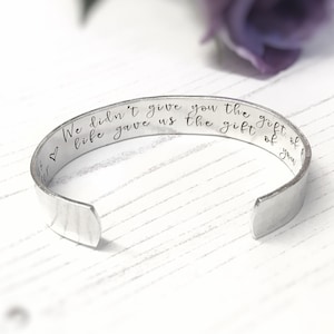 Puede incluir: Una pulsera de plata con un mensaje grabado que dice "We didn't give you the gift of life gave us the gift of you".