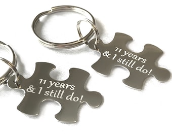 May include: Two silver puzzle piece keychains with the text "11 years & I still do!" engraved on each piece.