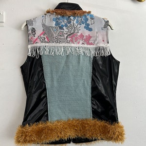 May include: A black sleeveless vest with a blue and white patterned fabric panel on the back. The vest has a brown fur collar and trim around the bottom.
