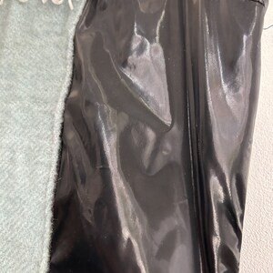May include: A black shiny fabric with a white and red trim. The fabric has a smooth, silky texture.