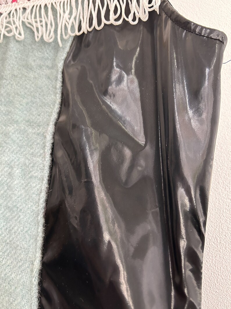 May include: A black shiny fabric with a white and red trim. The fabric has a smooth, silky texture.