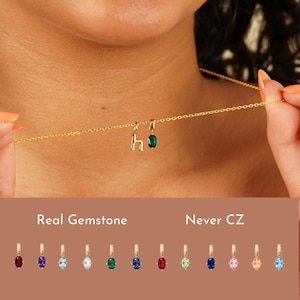 May include: A gold chain necklace featuring a lowercase letter h charm and an oval-cut green gemstone charm. Below, the text Real Gemstone Never CZ appears above a row of twelve individual oval-cut gemstone charms in various colors.