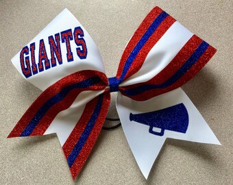 May include: White cheer bow with red and blue glitter stripes. The bow has the word "GIANTS" in blue letters on one side and a blue glitter megaphone on the other side.