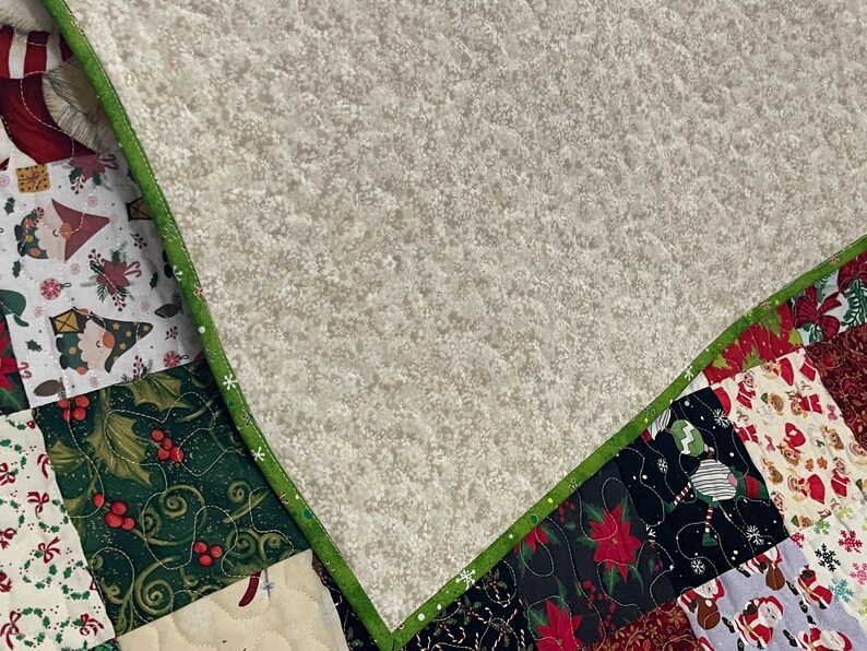 May include: A patchwork quilt with a variety of Christmas-themed patterns. The quilt features squares with images of Santa Claus, poinsettias, and gnomes. The quilt is trimmed with a green border.