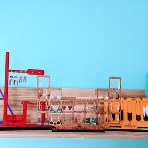 May include: A collection of earring displays made of wood and acrylic. The displays are shaped like beakers, test tubes, and a periodic table. The displays are filled with colourful earrings. The text "The Chemistry of Style" is on one of the displays.