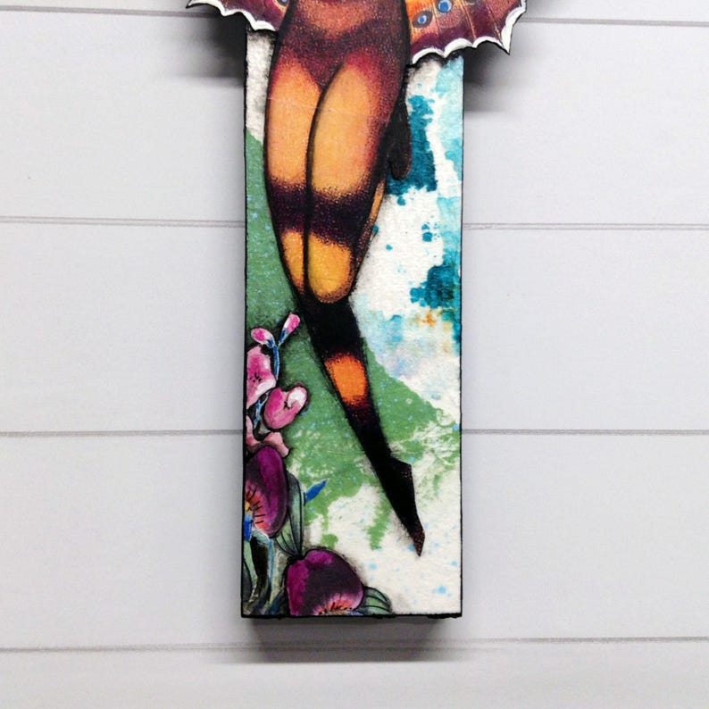 May include: A rectangular wall art piece featuring a stylized illustration of a moth with orange and black wings. The lower section displays vibrant purple and pink flowers against a textured white, green, and blue watercolor-style background.