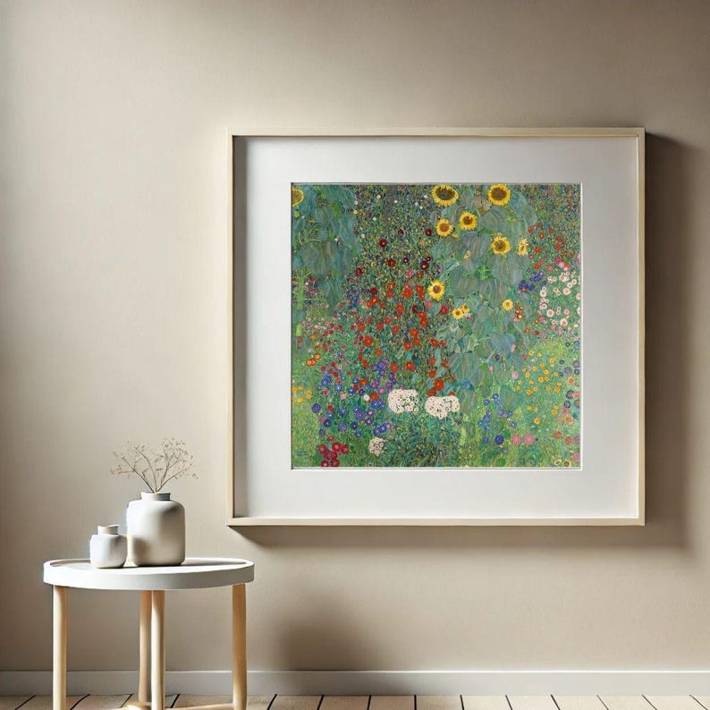 Puede incluir: Una impresi&oacute;n enmarcada de una colorida escena de jard&iacute;n, con girasoles y varias otras flores en tonos rojos, amarillos, blancos y azules. La obra de arte se exhibe en una pared beige, con una peque&ntilde;a mesa blanca y jarrones en primer plano.