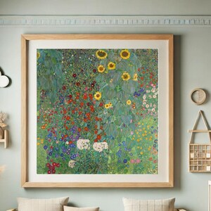 Puede incluir: Una impresi&oacute;n art&iacute;stica enmarcada que presenta una vibrante escena de jard&iacute;n floral. La obra de arte muestra girasoles, amapolas rojas y otras flores coloridas sobre un fondo de follaje verde. La impresi&oacute;n est&aacute; encerrada en un marco de madera clara.