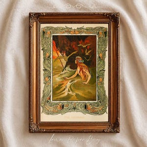 May include: Framed vintage art print featuring a mermaid in a sea scene. The artwork has a detailed border with floral and fish motifs. The print is in a gold-toned frame. The text "THE MERMAID" is at the bottom of the print.