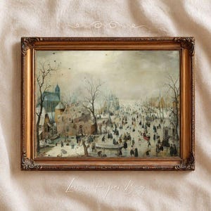 May include: A framed landscape painting depicting a winter scene with a frozen canal, numerous figures skating and walking, bare trees, and buildings under a pale sky. The artwork is enclosed in an ornate, metallic gold-toned rectangular frame.