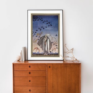 Peut inclure: Impression d'art encadr&eacute;e repr&eacute;sentant une figure en manteau long entour&eacute;e d'oiseaux. L'&oelig;uvre d'art pr&eacute;sente un sch&eacute;ma de couleurs bleu et or, avec un cadre noir et un passe-partout blanc. L'impression est expos&eacute;e sur un meuble en bois.