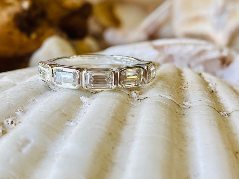 May include: A silver band ring with seven emerald-cut diamonds set in a row.