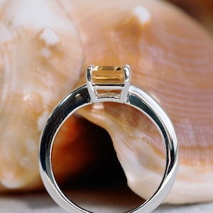 May include: A silver ring with a rectangular, light brown gemstone set in a simple, modern design.