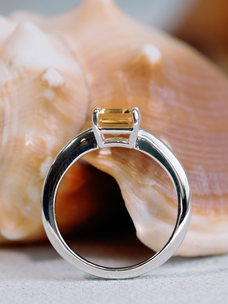 May include: A silver ring with a rectangular, light brown gemstone set in a simple, modern design.