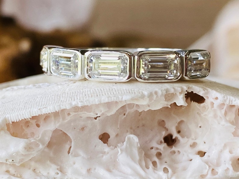 May include: A silver band ring with five emerald-cut diamonds set in a row.