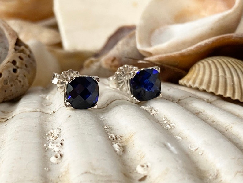 Puede incluir: Un par de pendientes de plata con piedras azules cuadradas.