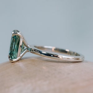May include: A silver ring featuring a large, emerald-cut green gemstone set in a prong setting.