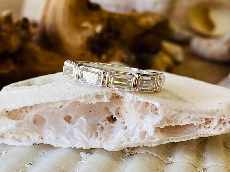 May include: A silver band ring with a row of emerald-cut diamonds.