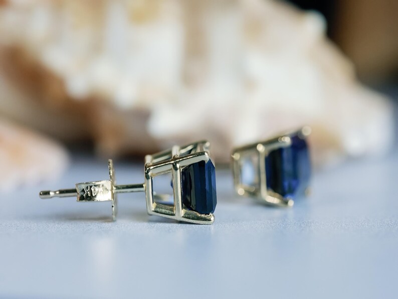Puede incluir: Un par de pendientes de oro con piedras preciosas de color azul oscuro. Los pendientes tienen un dise&ntilde;o simple y elegante.
