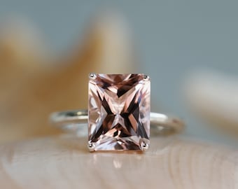 Könnte beinhalten: Ein Ring mit einem großen, quadratischen, hellrosa Edelstein, der in einer silbernen Fassung sitzt.