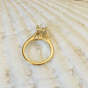 May include: A gold engagement ring with a square-shaped diamond.