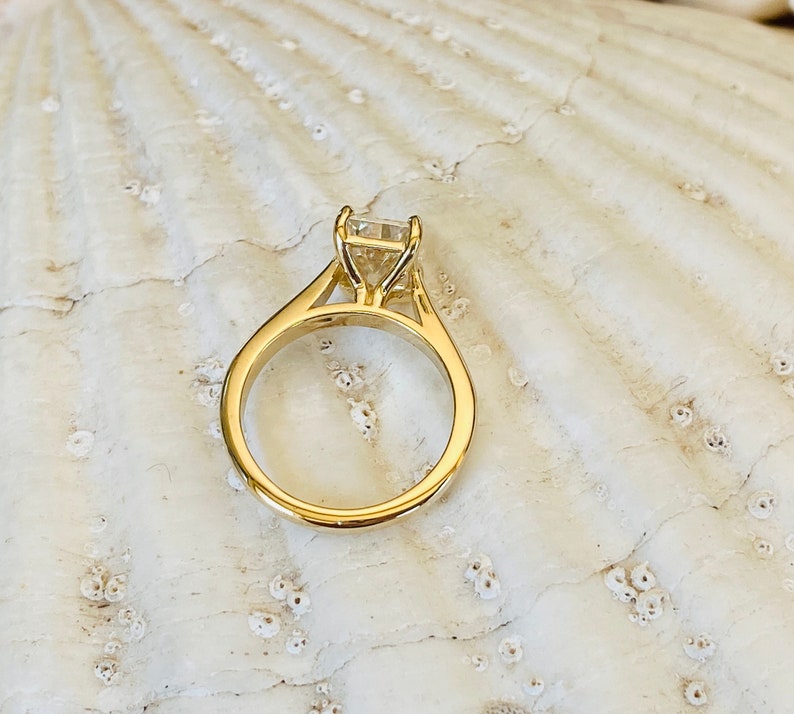 May include: A gold engagement ring with a square-shaped diamond.