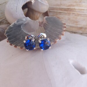 Puede incluir: Un par de pendientes de plata con piedras azules cuadradas.