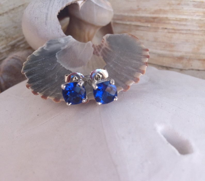 Puede incluir: Un par de pendientes de plata con piedras azules cuadradas.