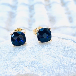 Puede incluir: Un par de pendientes de oro con piedras azules cuadradas.
