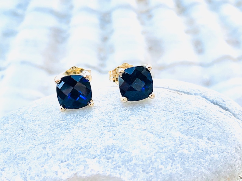 Puede incluir: Un par de pendientes de oro con piedras azules cuadradas.
