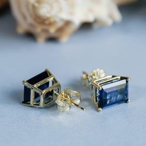 Puede incluir: Un par de pendientes de oro con detalles de piedras preciosas azules. Los pendientes tienen forma de rect&aacute;ngulo con un borde biselado.