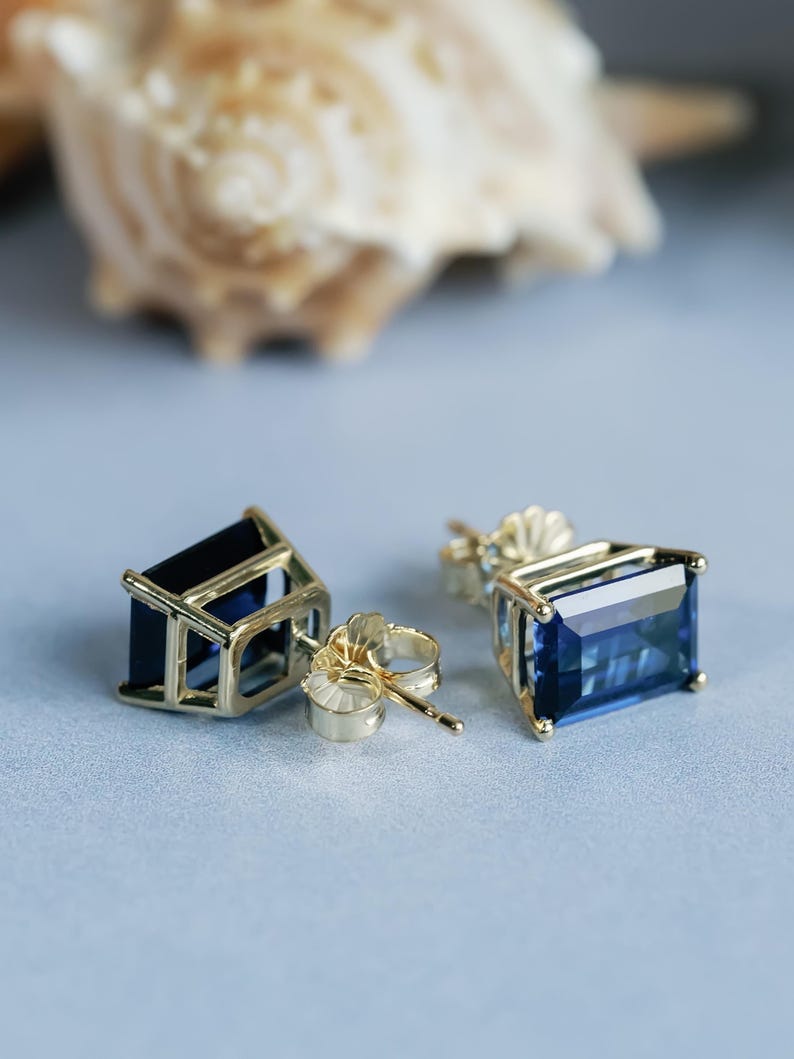Puede incluir: Un par de pendientes de oro con detalles de piedras preciosas azules. Los pendientes tienen forma de rect&aacute;ngulo con un borde biselado.