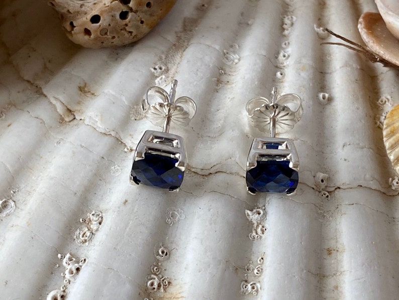 Puede incluir: Un par de pendientes de plata con una piedra preciosa azul cuadrada en cada pendiente.