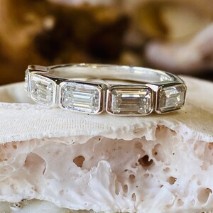 May include: A silver band ring with six emerald-cut diamonds set in a row.