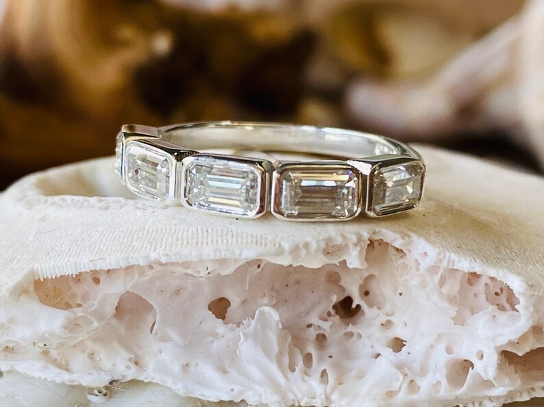 May include: A silver band ring with six emerald-cut diamonds set in a row.