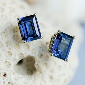 Puede incluir: Un par de pendientes de zafiro talla esmeralda engastados en oro. Los pendientes son de color azul intenso y tienen un acabado pulido.