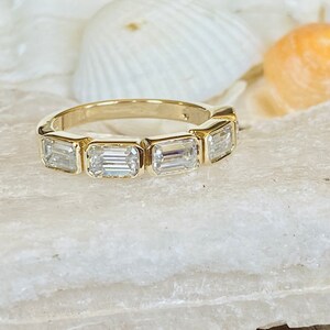 May include: A gold band ring with five emerald-cut diamonds set in a row.