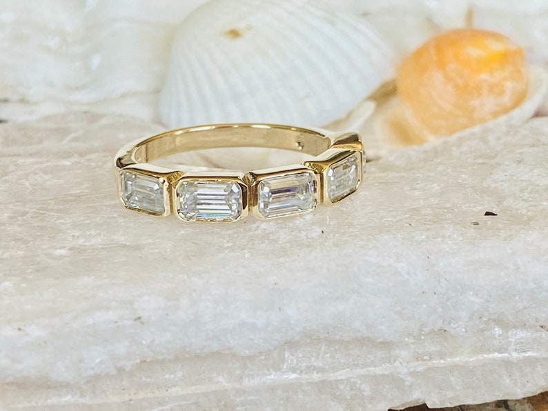 May include: A gold band ring with five emerald-cut diamonds set in a row.