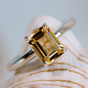May include: A silver ring with a large, rectangular, yellow citrine gemstone.