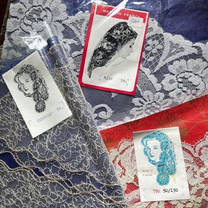 May include: Assortment of vintage lace fabric rolls in blue, red, and white. Each roll is accompanied by a tag with a woman's profile and the text "Made in France". The lace features intricate floral and abstract patterns.