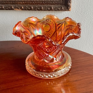 Puede incluir: Un cuenco de vidrio ámbar vintage con un borde rizado y un patrón de diamante. El cuenco tiene un acabado iridiscente y una base transparente.