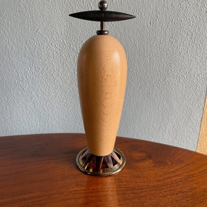 May include: A wooden pepper mill with a black knob on top and a gold metal base.